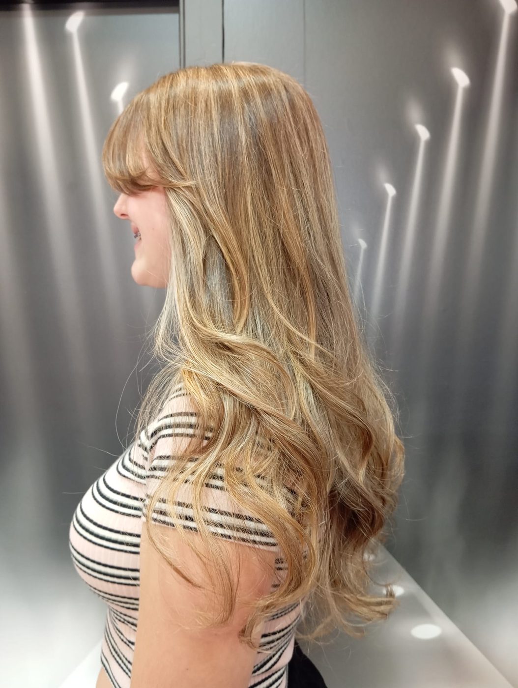 Melena rubia larga a capas con ondas, vista de perfil